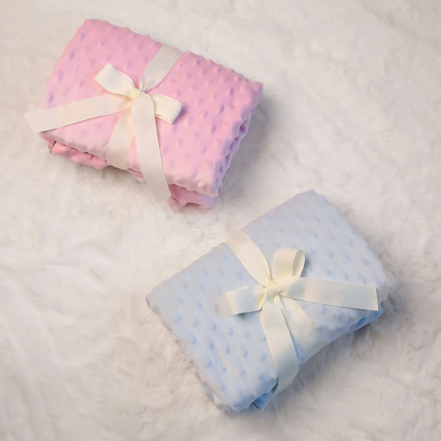 car seat ponchos folded and wrapped with white bows - pink and blue