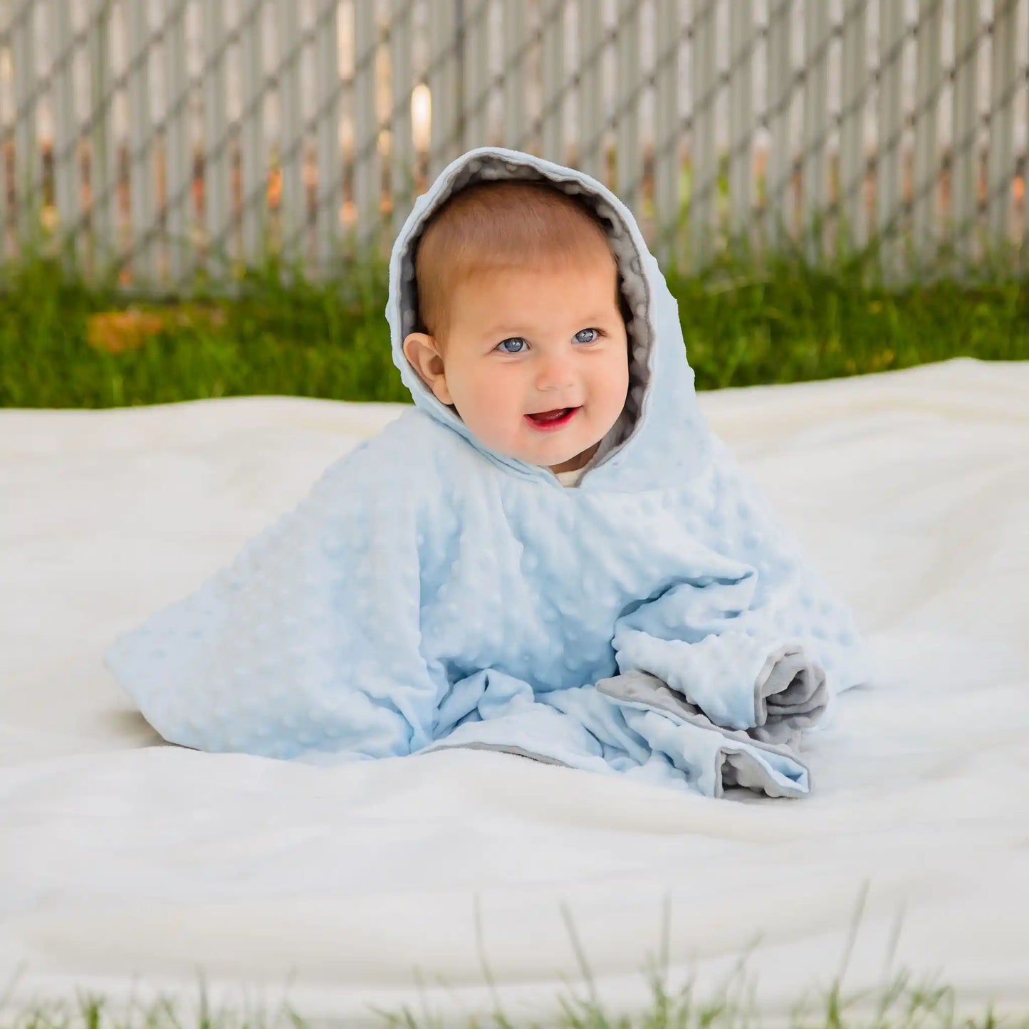 car seat poncho on baby boy sitting outside - blue