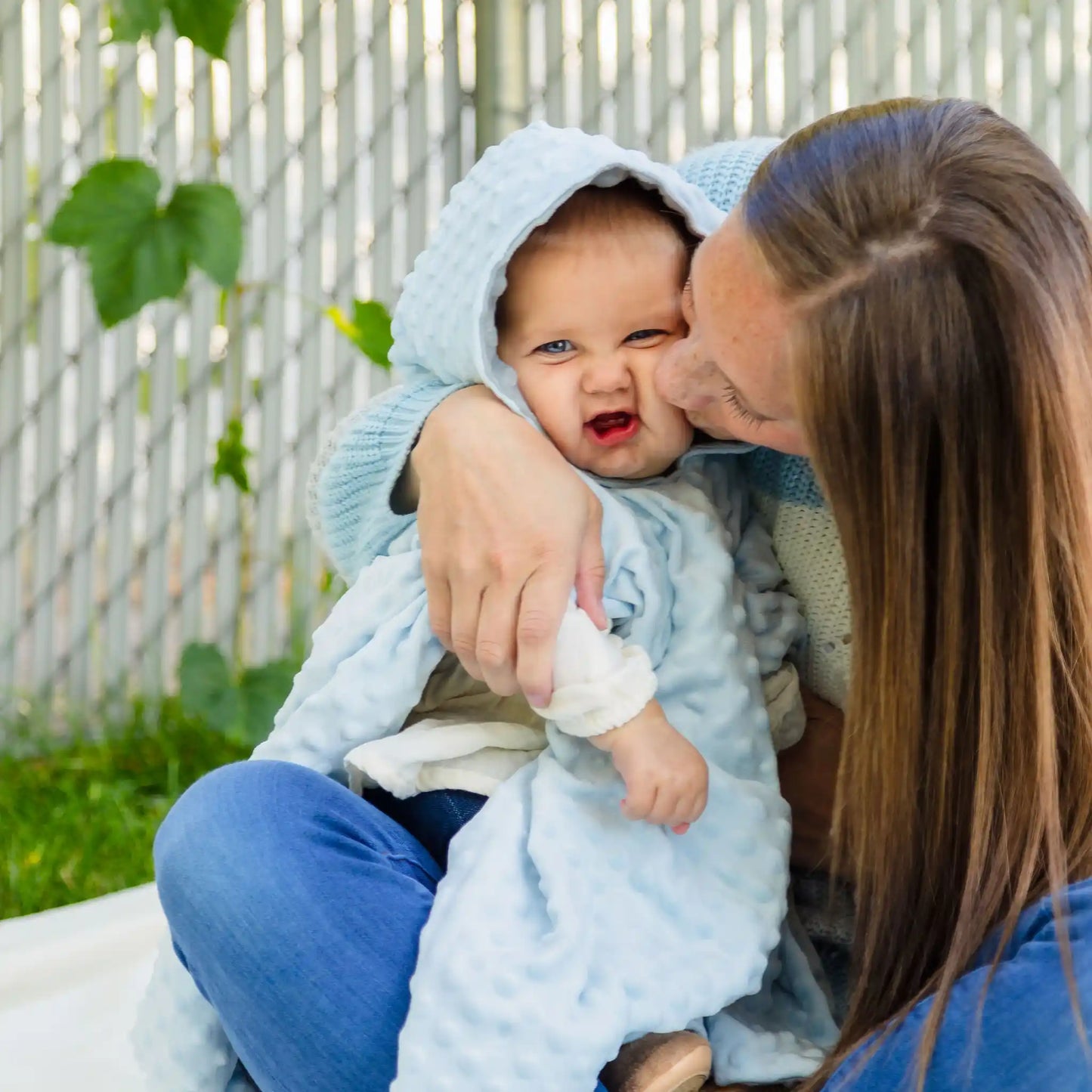 car seat poncho on baby boy with mother kissing his cheek - blue