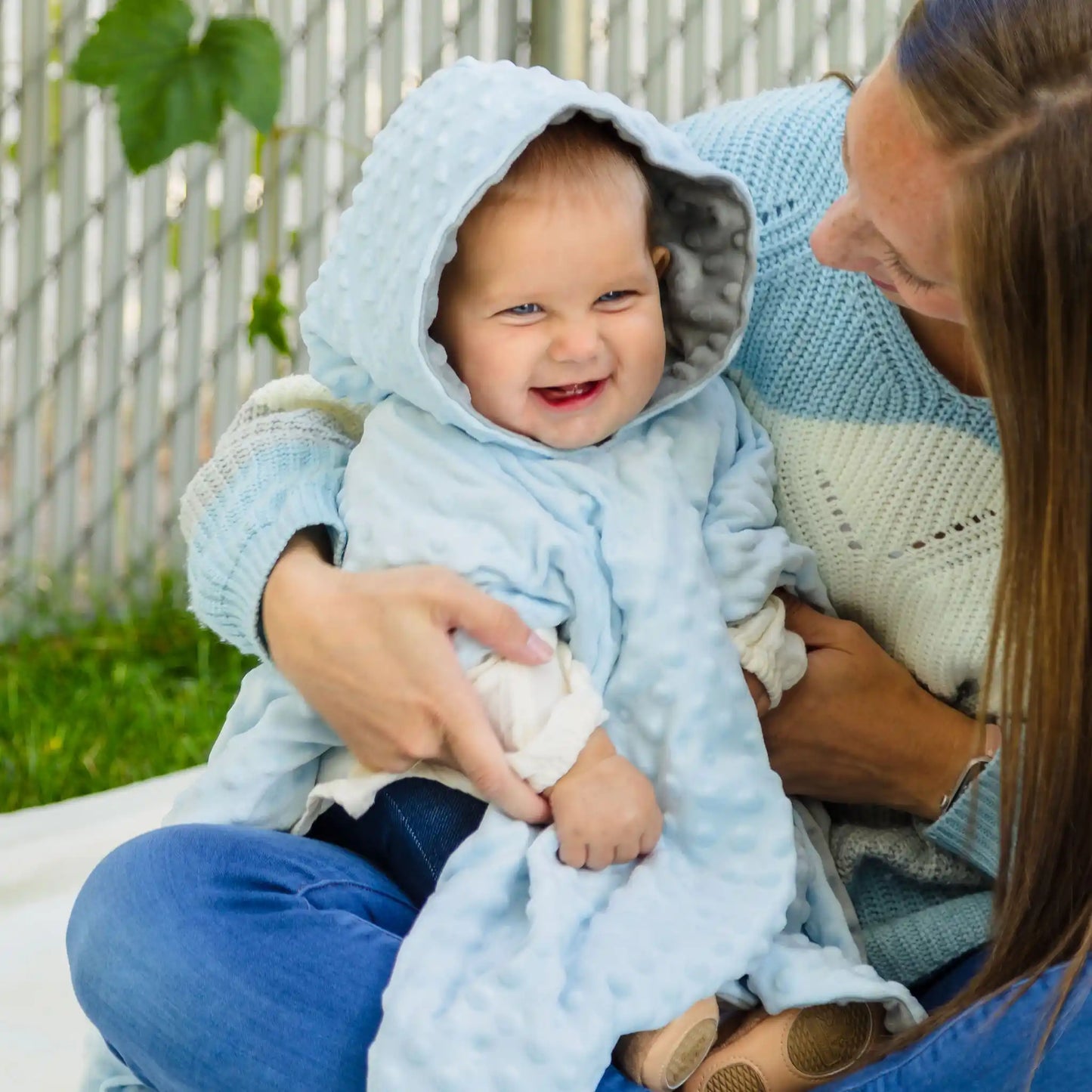 car seat poncho on baby boy with mother holding him - blue