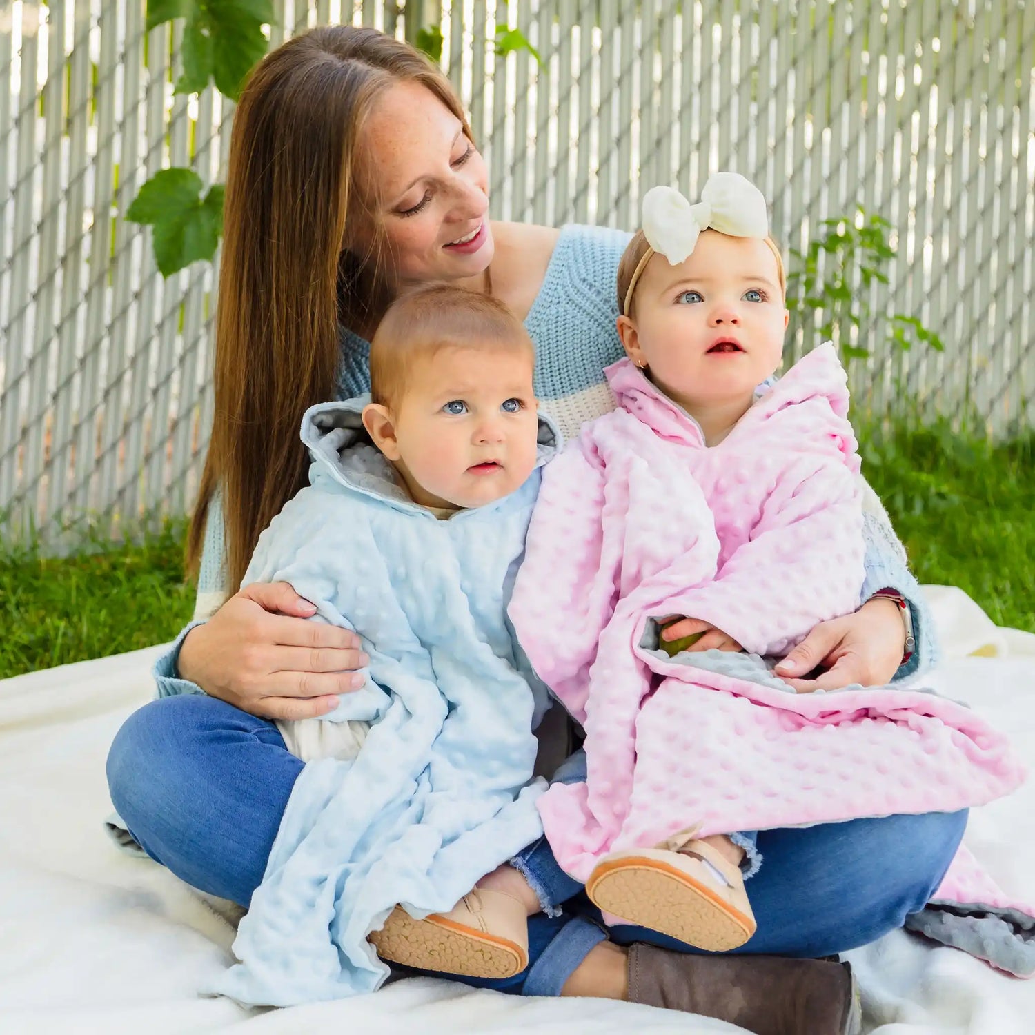 car seat ponchos on two baby girls with mother holding them - blue and pink