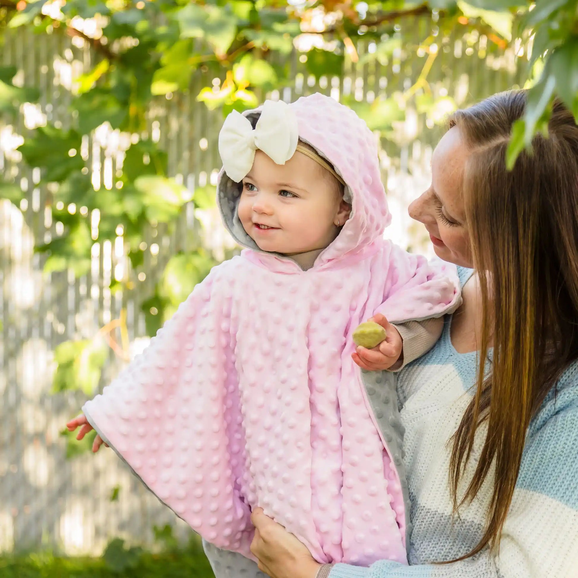 car seat poncho on baby girl with mother holding her - pink