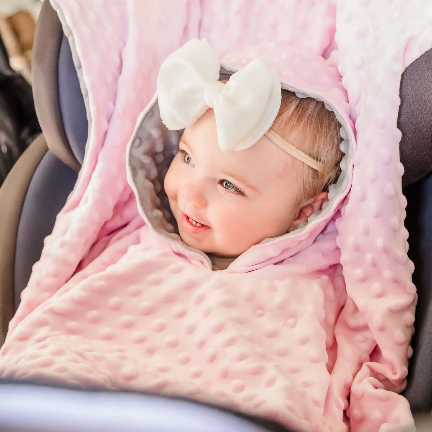 car seat blanket poncho on baby girl sitting in car seat - pink